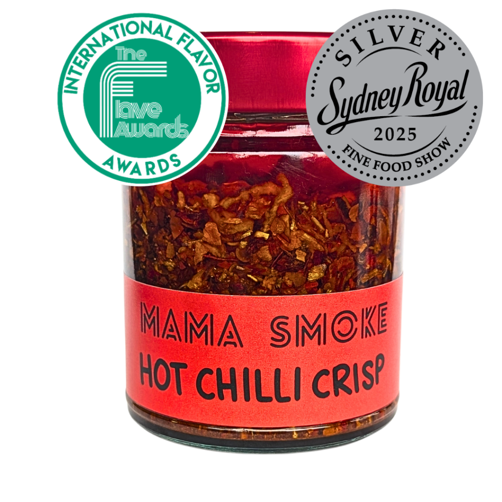 A glass jar of 'Mama Smoke' Hot Chilli Crisp with a red label and red lid. It features two award seals: Runner-up International Flavor Awards 2026, and 'Silver Sydney Royal Fine Food Show 2025' on a white background.