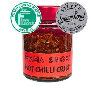 A glass jar of 'Mama Smoke' Hot Chilli Crisp with a red label and red lid. It features two award seals: Runner-up International Flavor Awards 2026, and 'Silver Sydney Royal Fine Food Show 2025' on a white background.